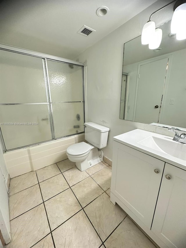 full bathroom featuring vanity, tile patterned flooring, bath / shower combo with glass door, and toilet