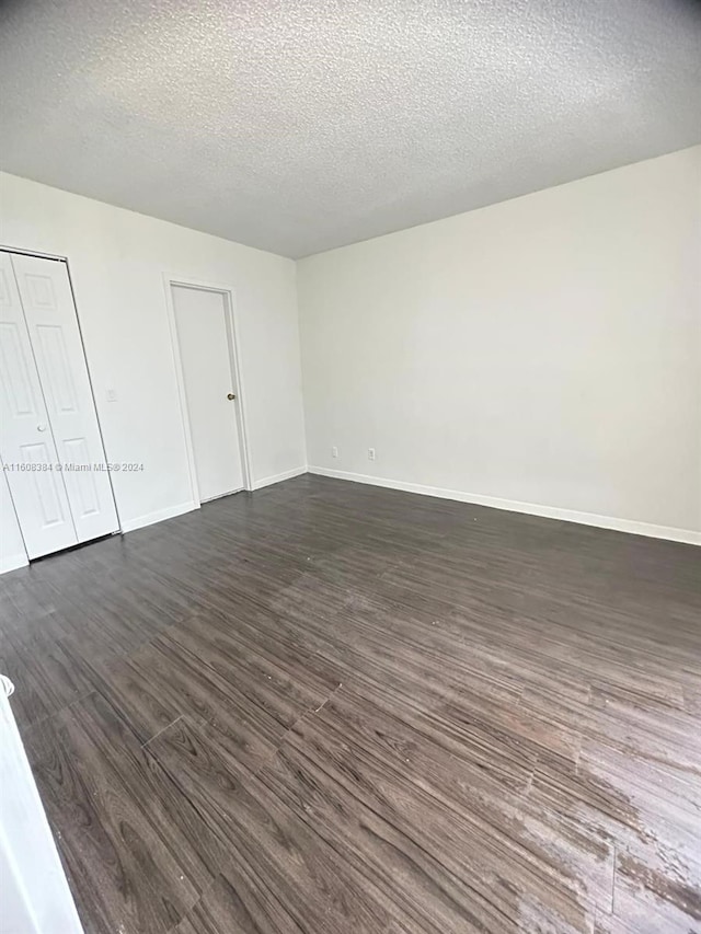 empty room featuring dark hardwood / wood-style flooring and a textured ceiling