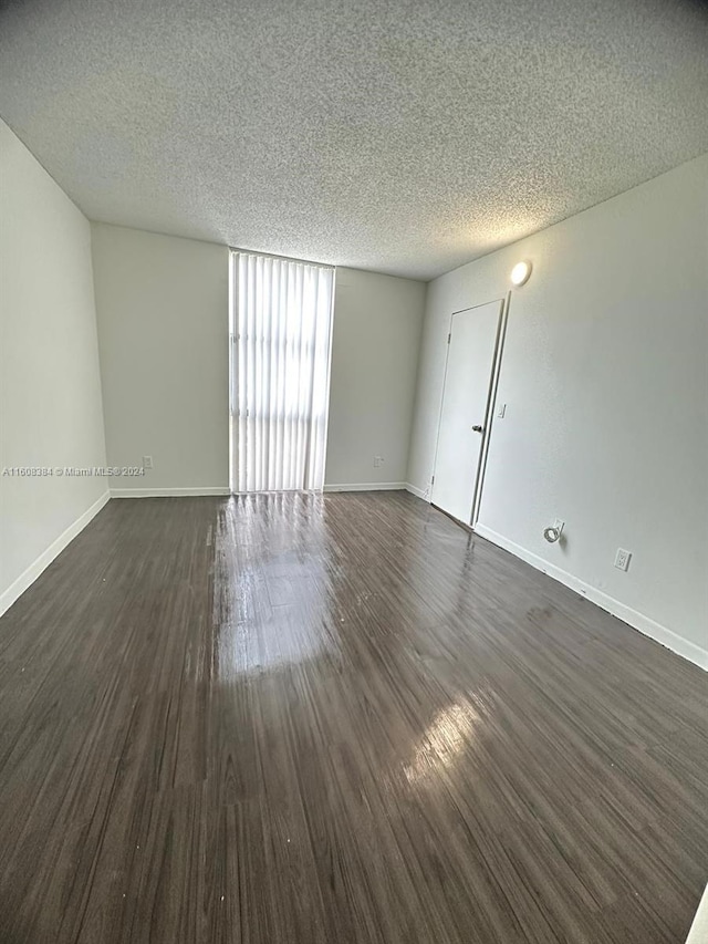 empty room with dark hardwood / wood-style floors and a textured ceiling