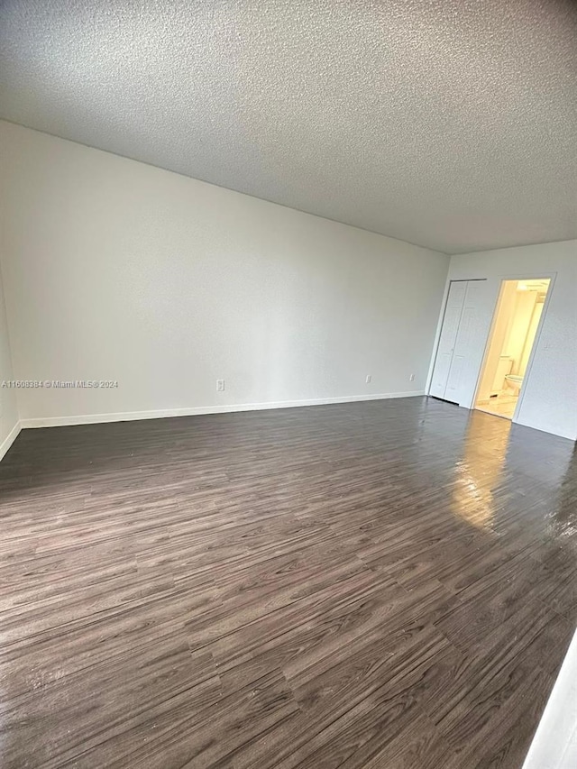 unfurnished room featuring a textured ceiling and dark hardwood / wood-style flooring