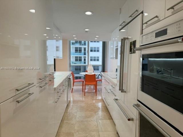 kitchen with expansive windows, white cabinets, and double oven