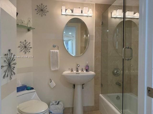 bathroom with toilet and shower / bath combination with glass door