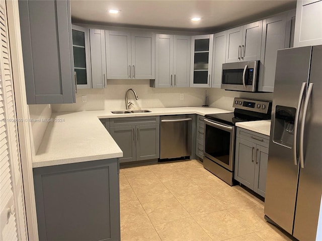 kitchen featuring gray cabinetry, light tile patterned floors, stainless steel appliances, and sink