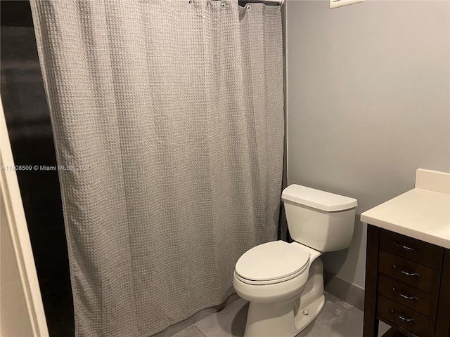 bathroom with a shower with shower curtain, vanity, toilet, and tile patterned floors