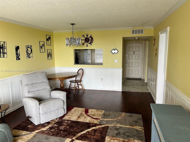 living room featuring a textured ceiling, dark hardwood / wood-style flooring, ornamental molding, and a notable chandelier