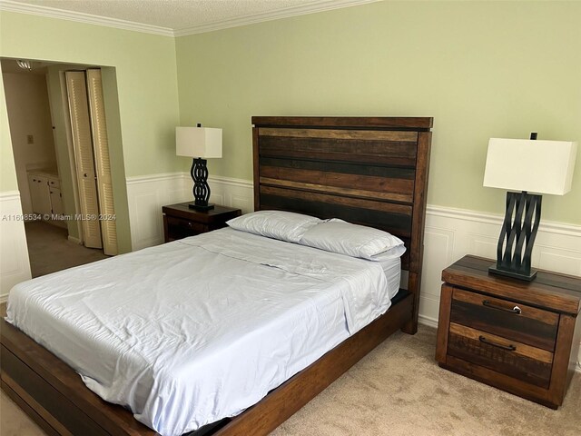 bedroom featuring light colored carpet, a textured ceiling, a closet, and crown molding