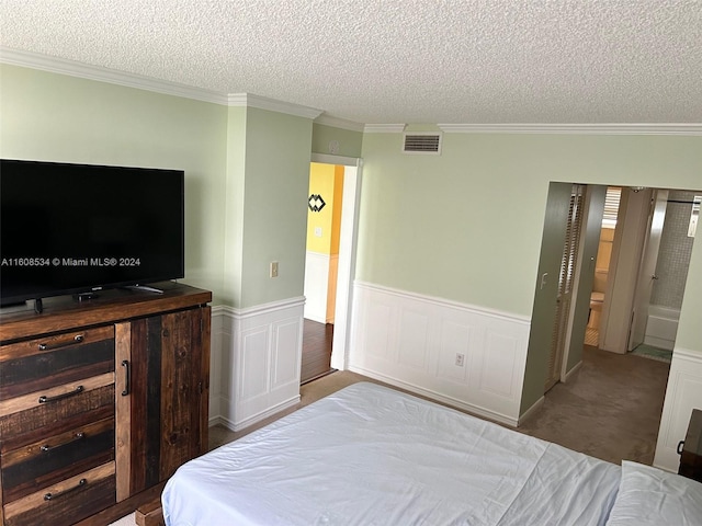 bedroom featuring ensuite bathroom, carpet, crown molding, and a textured ceiling