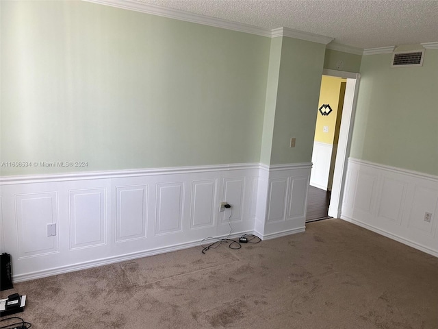 spare room featuring a textured ceiling, ornamental molding, and light colored carpet