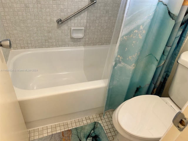 bathroom with toilet, shower / tub combo with curtain, and tile patterned flooring