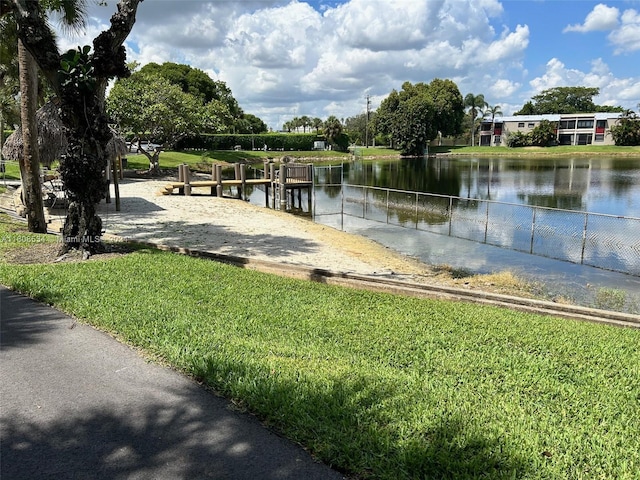 view of property's community with a water view and a lawn