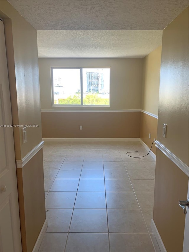 tiled spare room with a textured ceiling