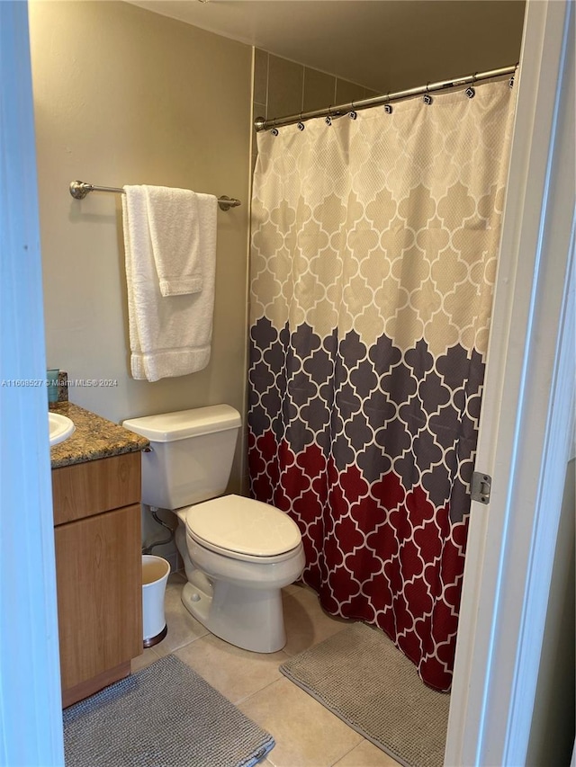 bathroom with toilet, vanity, and tile patterned flooring