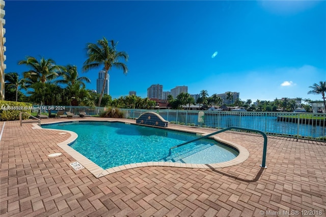 view of pool featuring a water view and a patio area