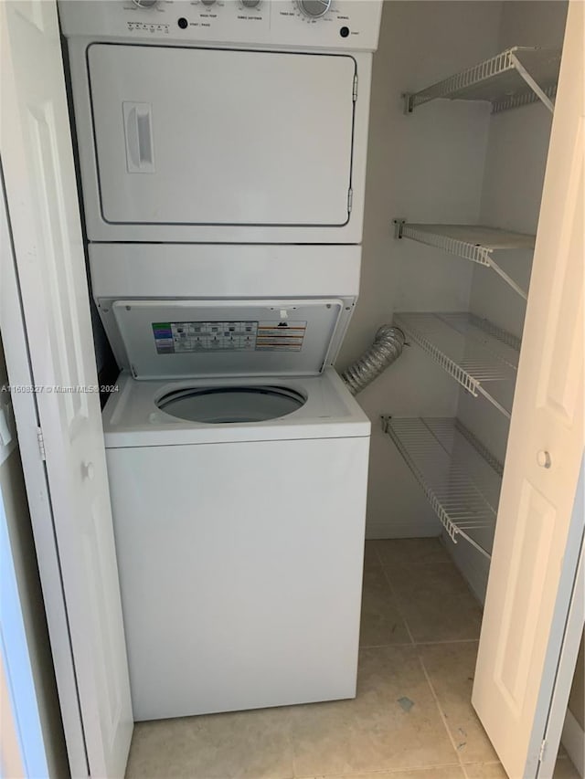 clothes washing area featuring light tile patterned floors and stacked washer and dryer