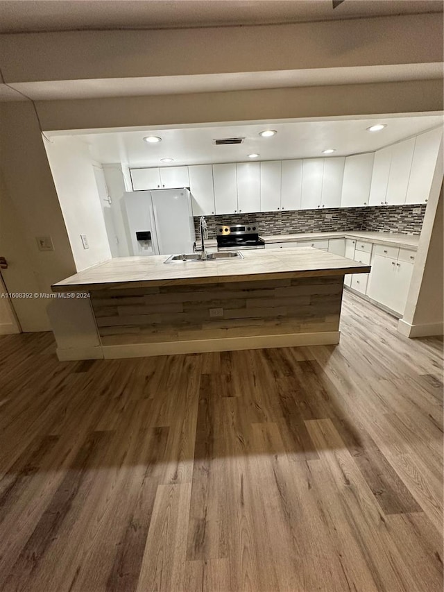 kitchen featuring white fridge with ice dispenser, tasteful backsplash, white cabinetry, light wood-type flooring, and sink