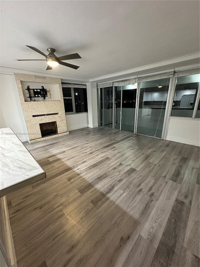 unfurnished living room with a textured ceiling, a fireplace, ceiling fan, and hardwood / wood-style floors