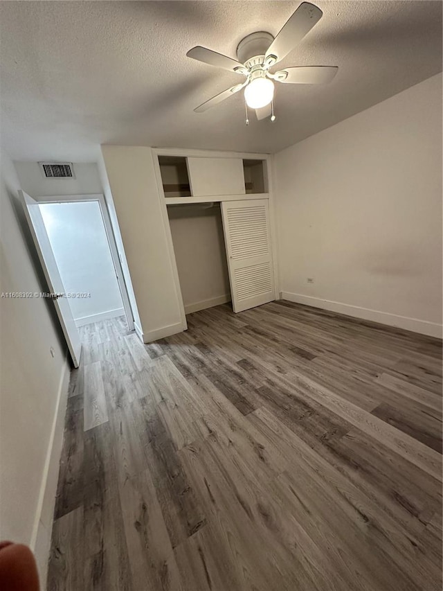 unfurnished bedroom featuring a textured ceiling, ceiling fan, a closet, and hardwood / wood-style floors