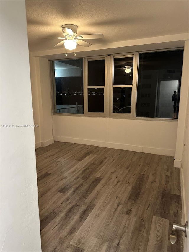 unfurnished room featuring a textured ceiling, dark wood-type flooring, and ceiling fan