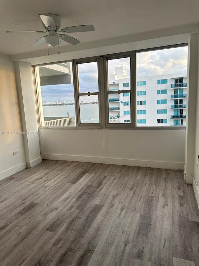 spare room with a healthy amount of sunlight, wood-type flooring, and ceiling fan