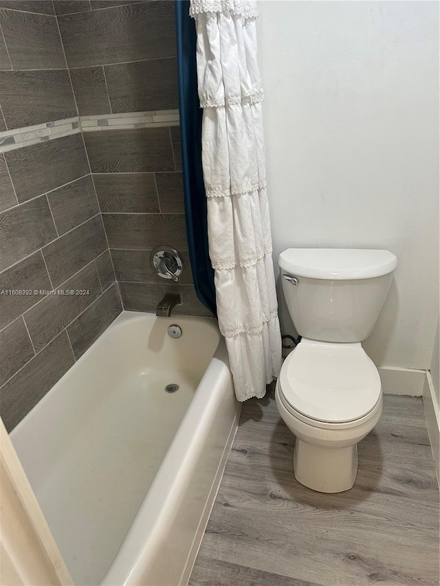 bathroom with wood-type flooring, toilet, and shower / bath combo with shower curtain