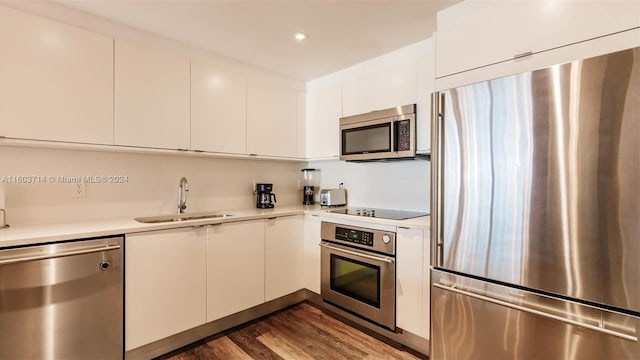 kitchen with stainless steel appliances, white cabinetry, dark wood-type flooring, and sink