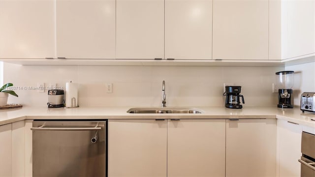 kitchen featuring decorative backsplash, sink, white cabinets, and stainless steel dishwasher