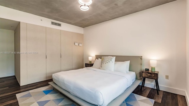 bedroom with dark hardwood / wood-style flooring and a closet