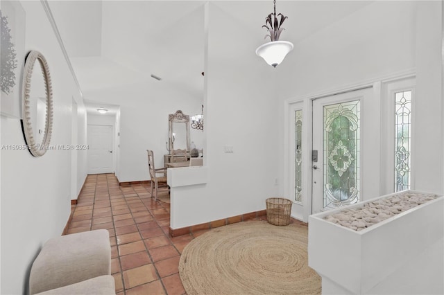 foyer with high vaulted ceiling, an inviting chandelier, and tile flooring