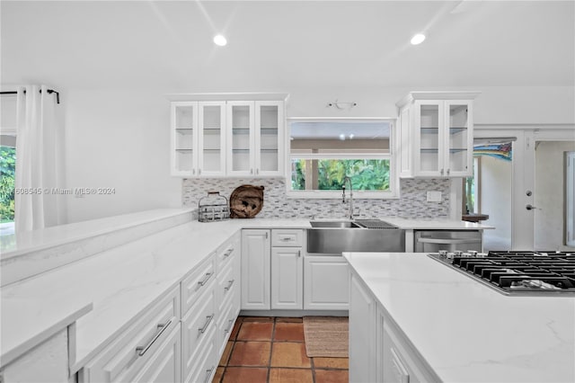 kitchen featuring stainless steel appliances, tasteful backsplash, tile floors, white cabinetry, and sink