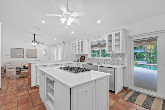 kitchen featuring appliances with stainless steel finishes, white cabinets, kitchen peninsula, backsplash, and ceiling fan