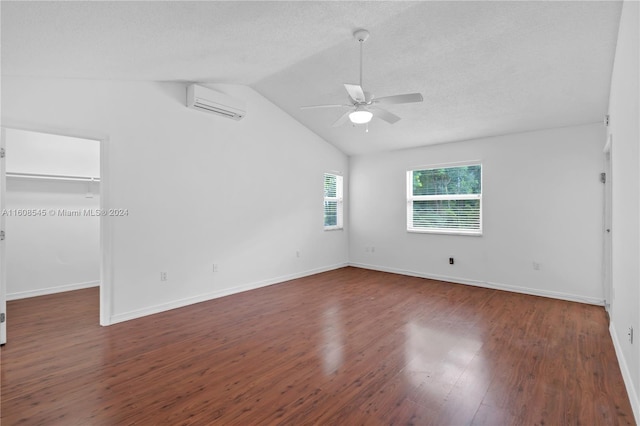 spare room with a wall unit AC, dark hardwood / wood-style flooring, ceiling fan, and lofted ceiling