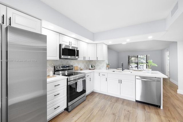 kitchen with stainless steel appliances, white cabinets, kitchen peninsula, and sink