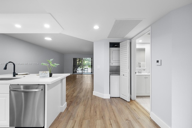 kitchen with light hardwood / wood-style floors, white cabinets, stacked washer and clothes dryer, stainless steel dishwasher, and sink