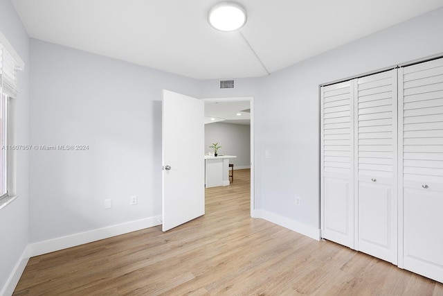 unfurnished bedroom with light wood-type flooring and a closet