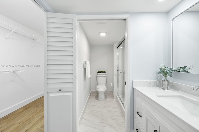 bathroom with vanity, a shower with shower door, toilet, and hardwood / wood-style flooring