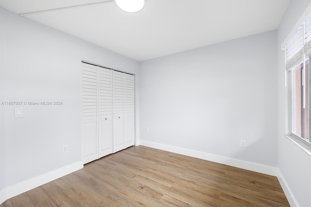 unfurnished bedroom with light wood-type flooring and a closet