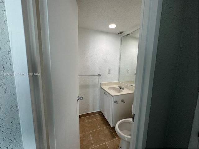 bathroom featuring tile patterned floors, toilet, a textured ceiling, and vanity