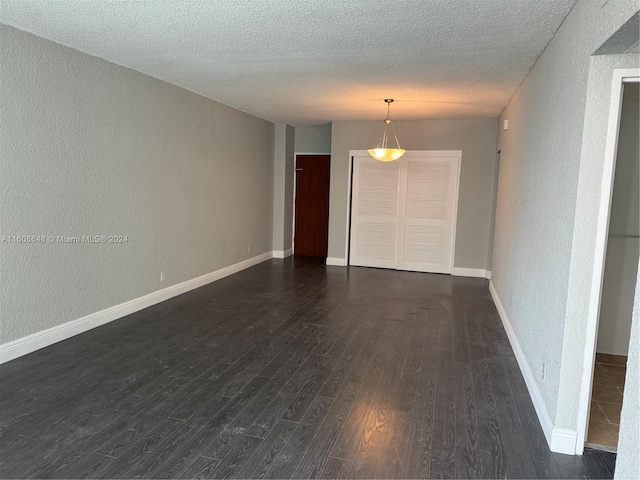 empty room featuring a textured ceiling and dark wood-type flooring