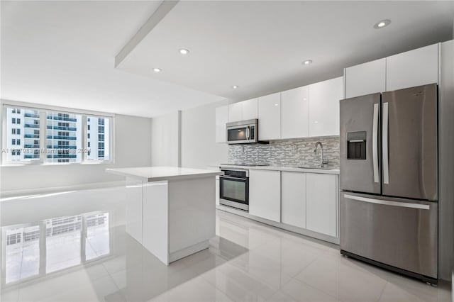 kitchen featuring tasteful backsplash, stainless steel appliances, light tile floors, sink, and white cabinets