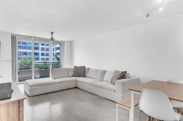 living room with concrete flooring, rail lighting, ceiling fan, and floor to ceiling windows