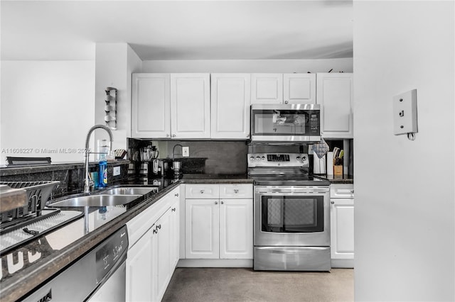 kitchen with white cabinets, stainless steel appliances, dark stone counters, and sink