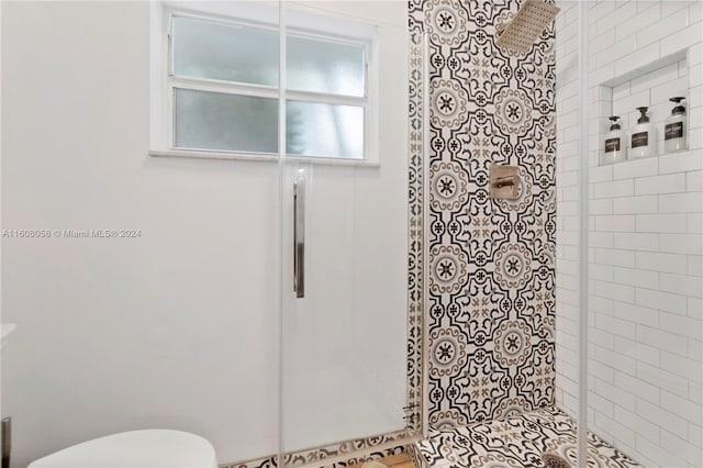 bathroom featuring a shower with door and toilet