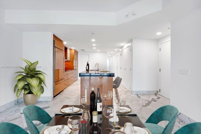 kitchen with sink, wall chimney range hood, expansive windows, built in appliances, and a center island with sink