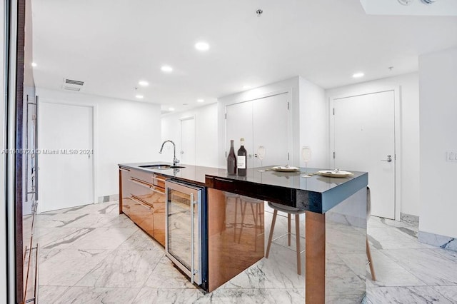 kitchen featuring sink, a kitchen island with sink, and wine cooler