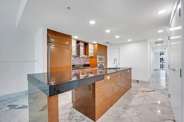 kitchen with built in appliances, marble finish floor, dark countertops, wall chimney exhaust hood, and modern cabinets