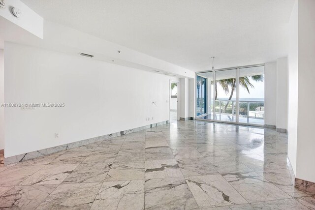 empty room with expansive windows, a water view, and a healthy amount of sunlight