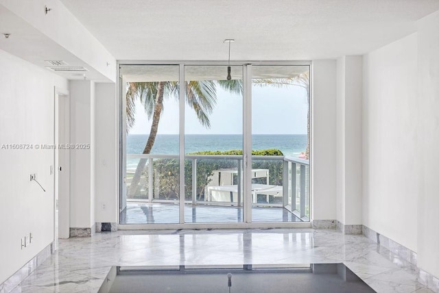 empty room featuring a water view, marble finish floor, visible vents, and a wall of windows