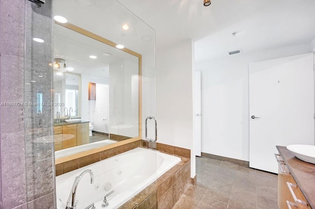 bathroom featuring visible vents, toilet, vanity, and a whirlpool tub