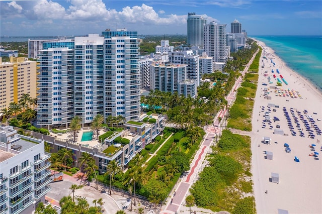 drone / aerial view featuring a water view, a view of city, and a view of the beach