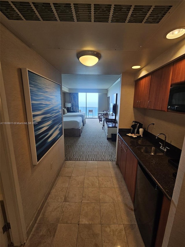 kitchen with dark stone countertops, light colored carpet, dishwasher, and sink